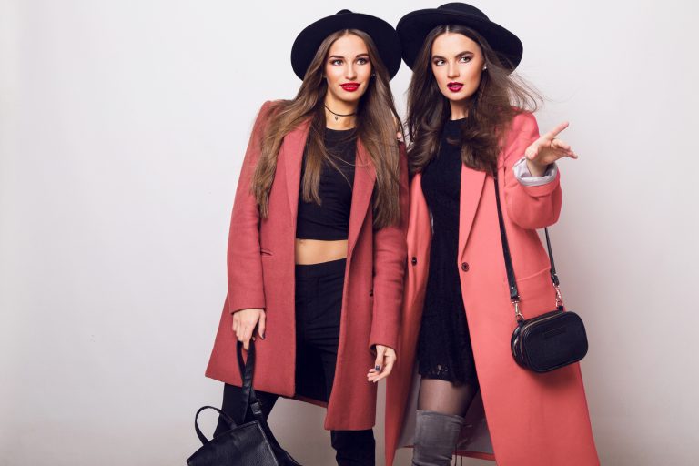 Two attractive young models in casual spring outfit, pink coat . Fashion trendy look. Bright make up. Brunette long hairs.